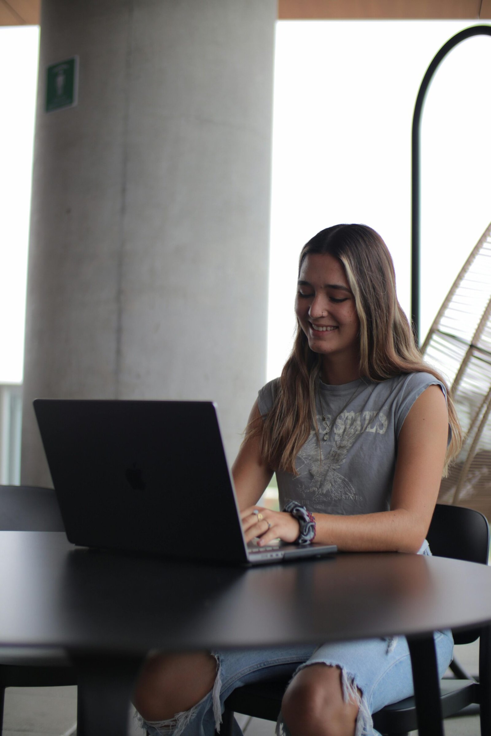 Young woman using a laptop in a modern indoor setting, focused on online study.